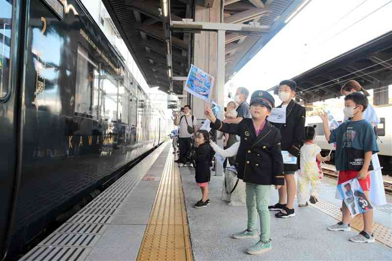 駅員の制服を着て特急「かわせみやませみ」を送り出す子どもたち＝20日、熊本市西区