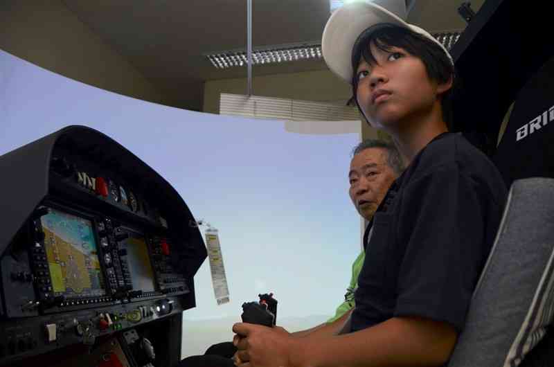 フライトシミュレーターで操縦を体験する子ども（手前）＝20日、菊陽町