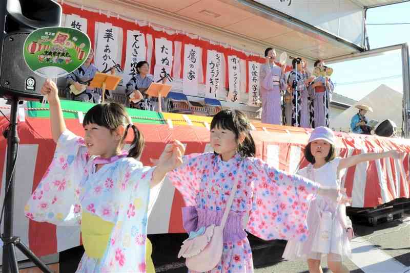 地域住民による演奏と歌に合わせて、「植木わくわく夏祭り音頭」を踊る植木小の児童ら＝20日、熊本市北区
