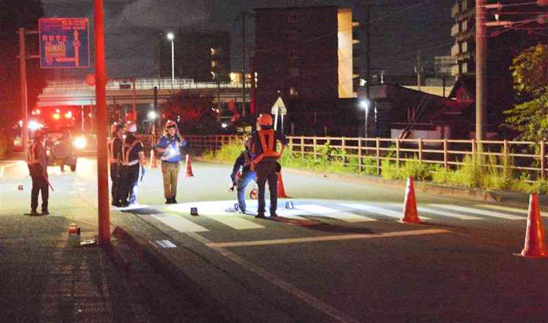 歩行者2人が軽乗用車にはねられ死傷した事故現場を調べる警察官ら＝21日午前2時ごろ、熊本市北区