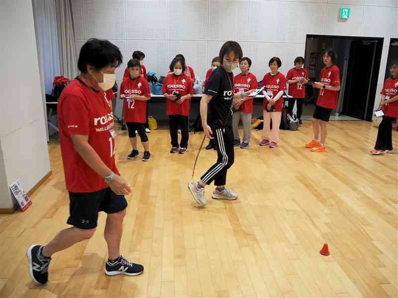 介護予防を目的とした運動プログラムで、歩行能力測定を受ける参加者（左）＝17日、熊本市中央区