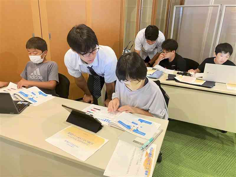子どもたちに優しくプログラミングを教える熊本高専の学生たち＝昨年9月、熊本市中央区
