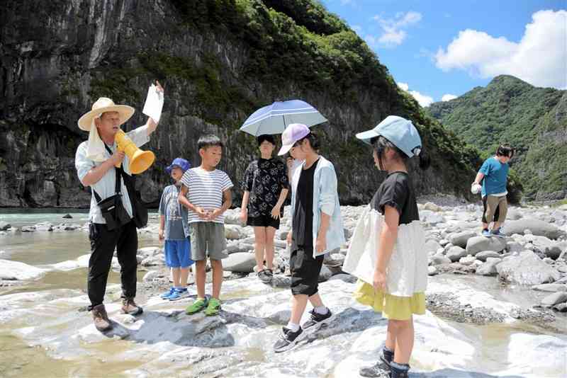 児童らにメガロドンの化石について説明する村本雄一郎さん（左端）＝７月21日、球磨村