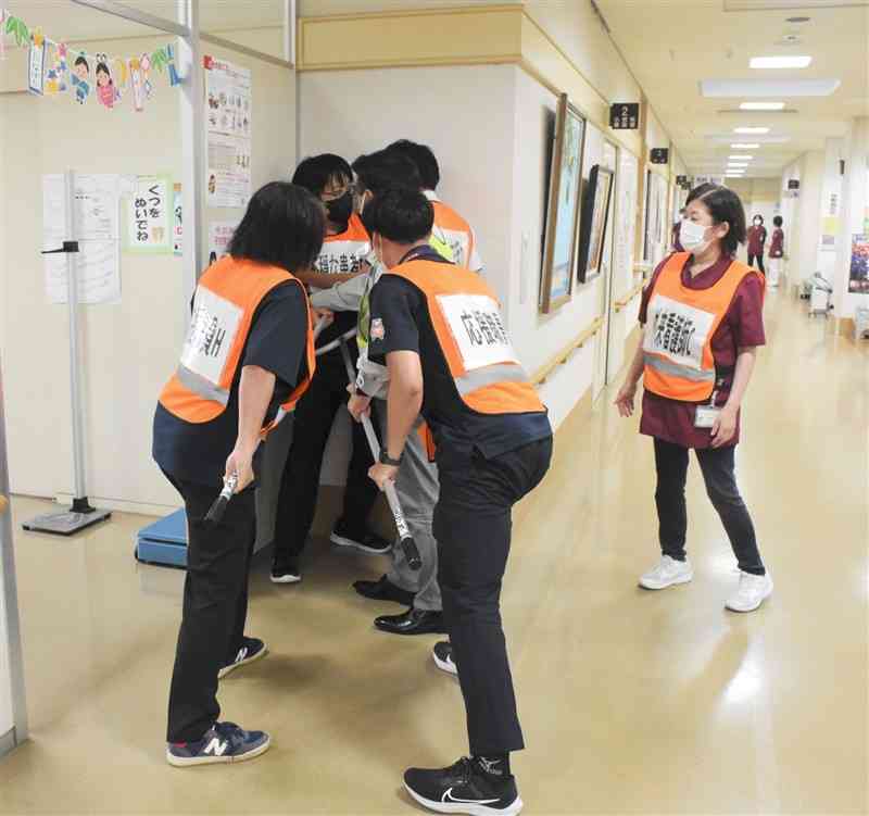 和水町立病院の「ペイハラ」対応訓練で、刺股を使って暴言を吐く患者役を制する職員たち＝25日、同町