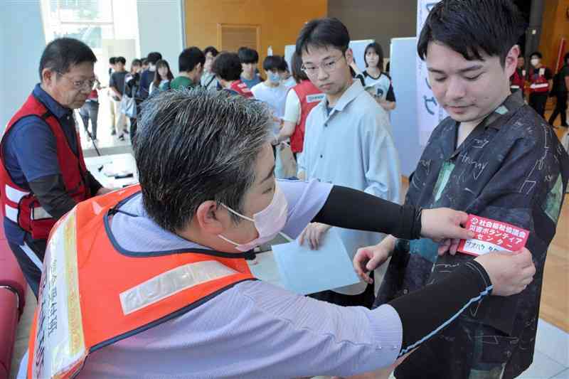 災害ボランティアセンターの運営訓練で受け付けをする大学生（右）＝27日、熊本市中央区
