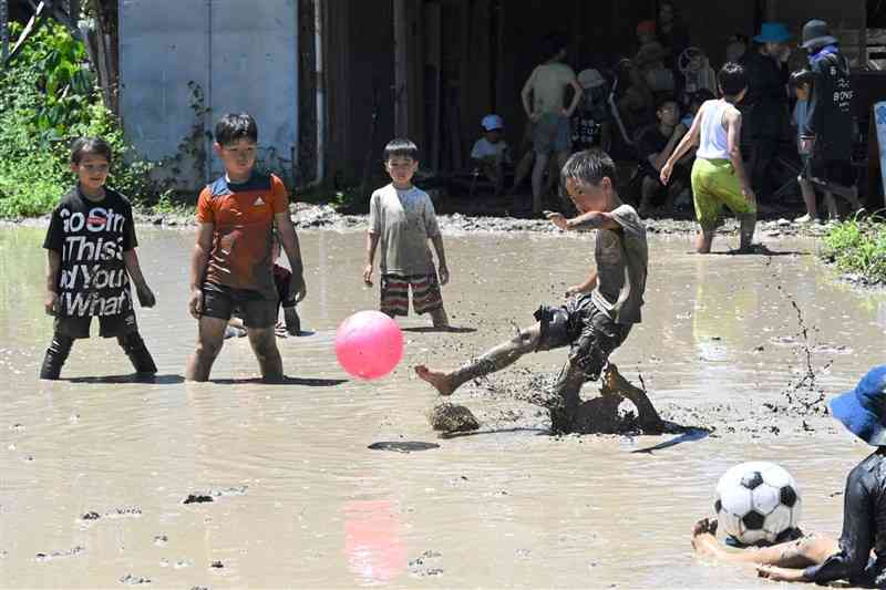 田んぼPK大会で、泥だらけになりながらボールを蹴る子どもたち＝７月27日、菊池市