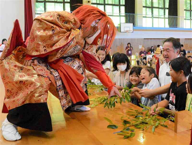 波野中生徒による中江岩戸神楽の「柴曳」で、サカキを引っ張る体験をする沖縄の子どもたち＝7月29日、阿蘇市