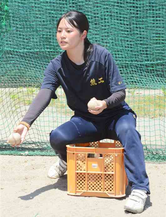 選手に打撃練習のトスを上げるマネジャーの豊永はるさん＝28日、熊本市中央区