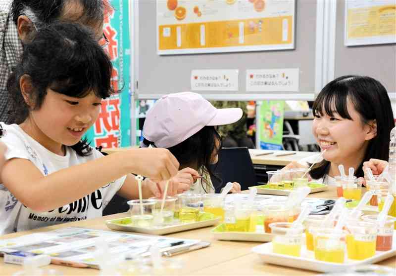 ビタミンC入りの果汁を垂らしてうがい薬の色を透明にする実験を楽しむ子どもら＝７月31日、熊本市西区