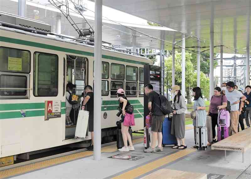 熊本市電を利用するインバウンド（訪日客）で混み合う熊本駅前電停＝7月17日、熊本市西区