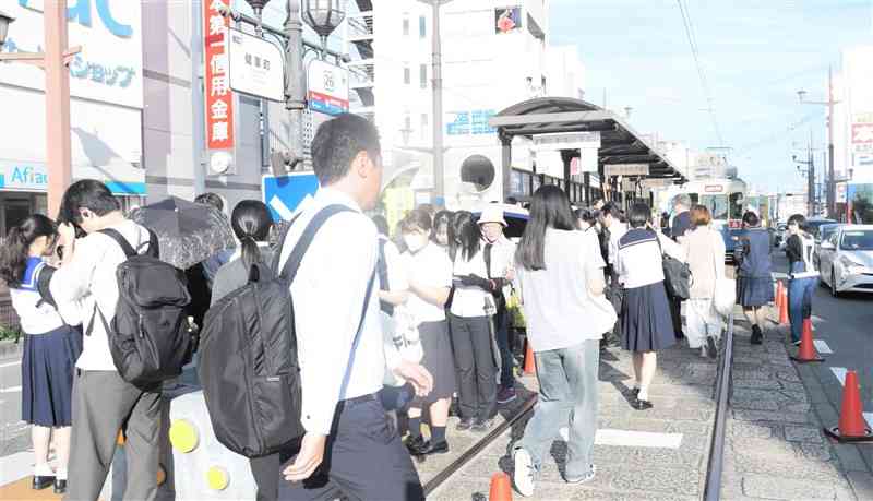 通勤・通学で熊本市電を利用する客で混み合う朝の健軍町電停＝7月17日、熊本市東区