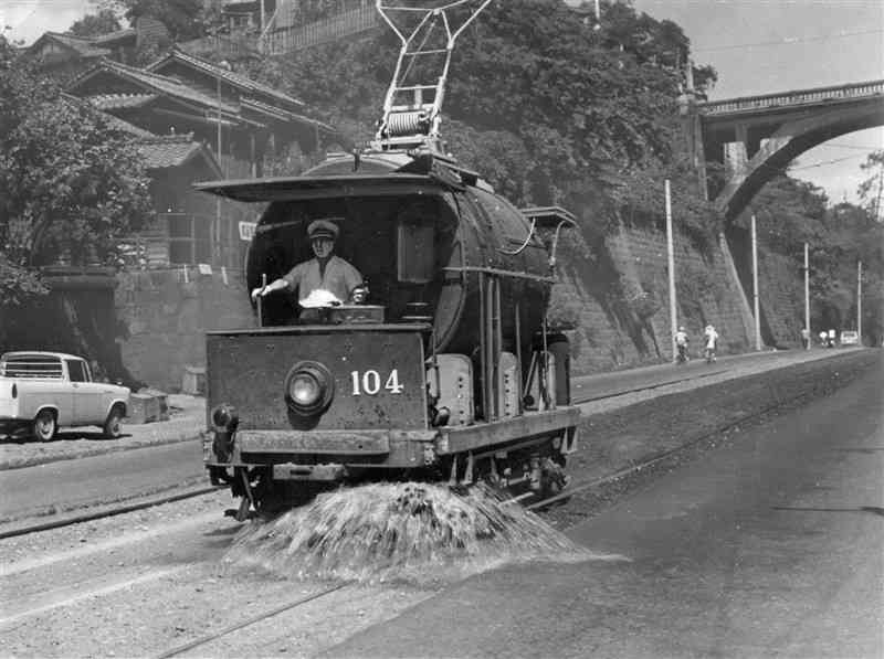 1964年ごろ、熊本城近くを走る散水車。当初は市役所近くで坪井川の水をくみ上げていたが、市立体育館前の専用井戸の水を使うよう変更されたという＝熊本市