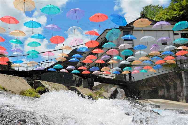 湯の鶴温泉にお目見えした色とりどりの傘の数々。湯出川のせせらぎが聞こえる＝7月25日、水俣市