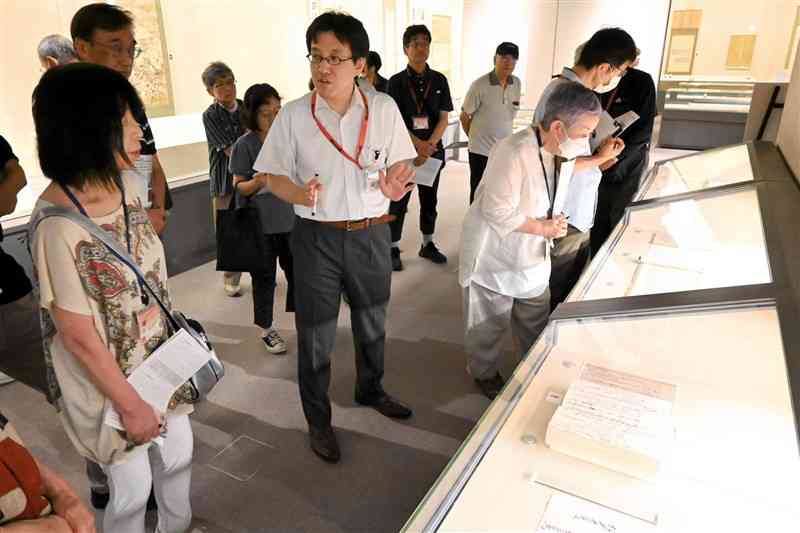 福井市立郷土歴史博物館の夏季特別展で展示品の説明をする山田裕輝学芸員（中央）＝7月19日、福井市