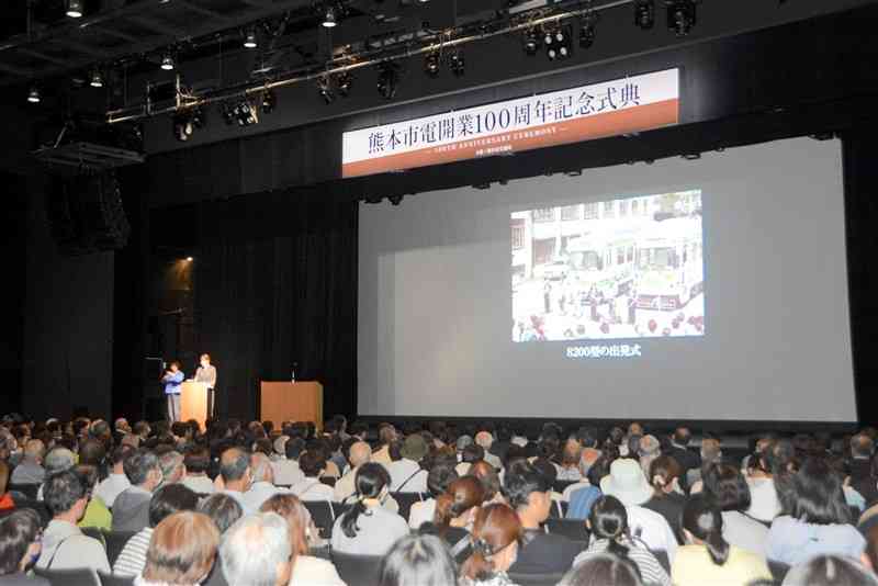 熊本市電開業100周年を記念して、市交通局が開いた式典。参加した約500人の市民らと、写真で100年の歴史を振り返った＝1日、熊本市中央区の熊本城ホール