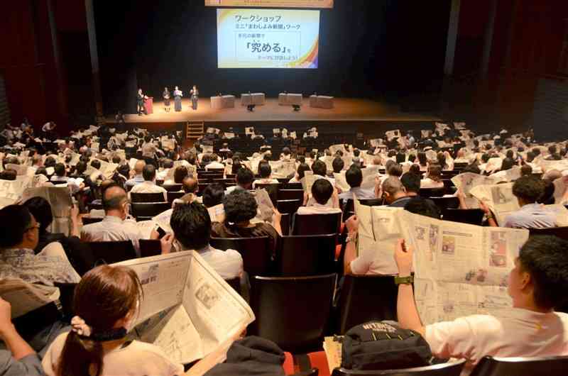 NIE全国大会京都大会で新聞を広げて気になる記事を探す参加者＝京都市のロームシアター京都