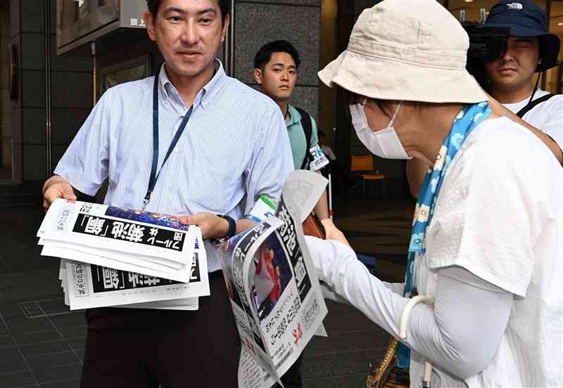 パリ五輪フェンシング女子フルーレ団体で、県勢の菊池小巻選手が銅メダルを獲得したことを報じる熊日号外を受け取る通行人＝2日午前11時ごろ、熊本市中央区（石本智）