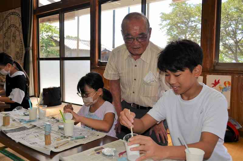 20年を迎えた「子どもつどい広場」でレプリカの化石作りを楽しむ子どもたち。右から2人目は広場を始めた平野俊昭さん＝7月28日、宇城市