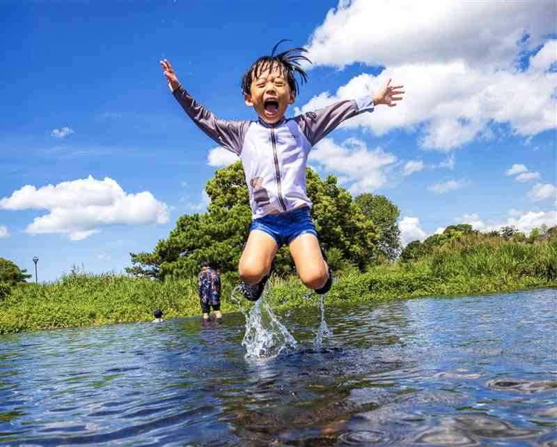 　【特選】「夏空にジャンプ」前田高光（71）　熊本市（熊本個人1478）▽有効画素数4500万、レンズ15～35ミリ、ISO400、絞り8、1250分の1秒　【評】夏空広がる江津湖で、飛び跳ねる親戚の子どもを活写しました。画面を少し傾かせることで躍動感が生まれ、満面の笑みと相まって元気いっぱいに遊んでいる様子が伝わります。「熊本の夏」をストレートに表現した気持ちのいい作品です。