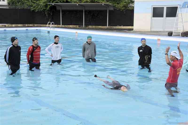 水難学会指導員の杉谷健さん（右）から「浮いて待つ」体勢を学ぶ後藤幸樹記者（左）ら参加者＝4日、熊本市南区（松冨浩之）