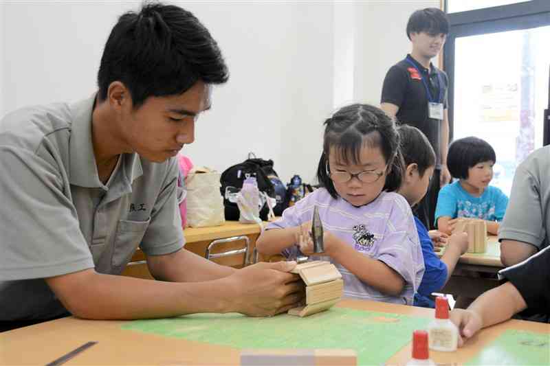 熊本工高生にかなづちの使い方教えてもらいながら、くぎを打つ小学生＝6日、熊本市東区