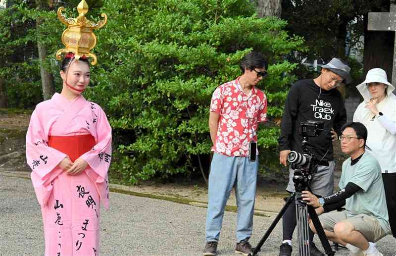 金灯籠を頭に載せた山鹿灯籠踊り保存会の女性を撮影する韓国のテレビ局の取材クルー＝6日、山鹿市