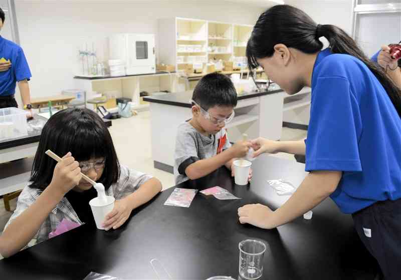 熊本工高の生徒に教わりながらスライムを作る子どもたち＝8日、熊本市中央区