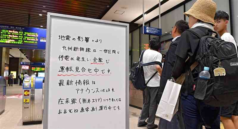 地震による停電で、九州新幹線の運転見合わせを知らせるホワイトボードを確認する利用客＝8日午後5時15分ごろ、熊本市西区のJR熊本駅（上杉勇太）