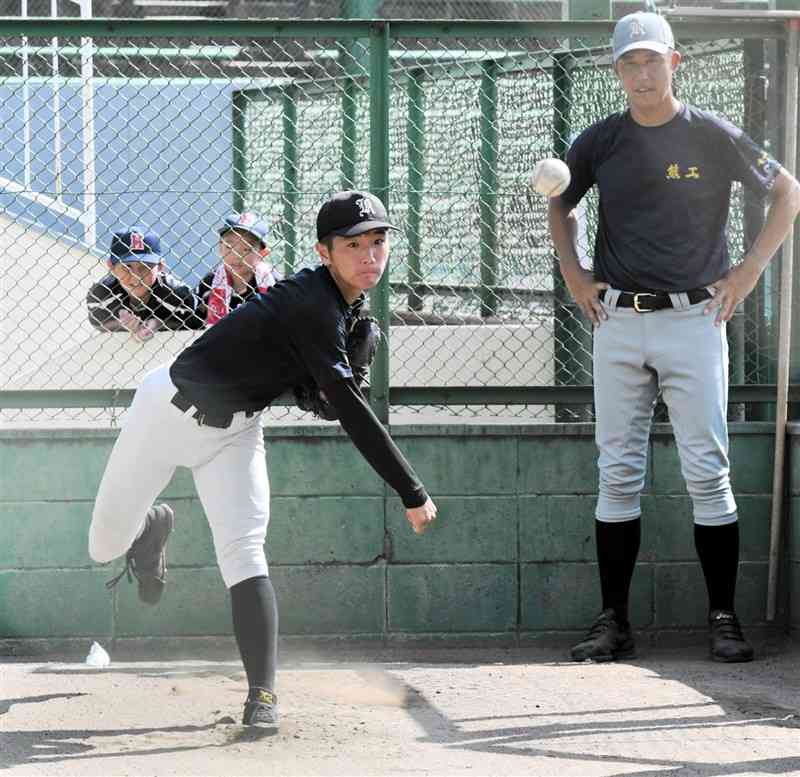 田島圭介監督（右）が見守る中、ブルペンで投げ込む熊本工の山本凌雅＝10日、兵庫県伊丹市