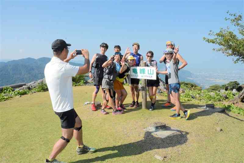 竜峰山頂で記念撮影する「やっちろドラゴントレイル」の出場者＝11日、八代市