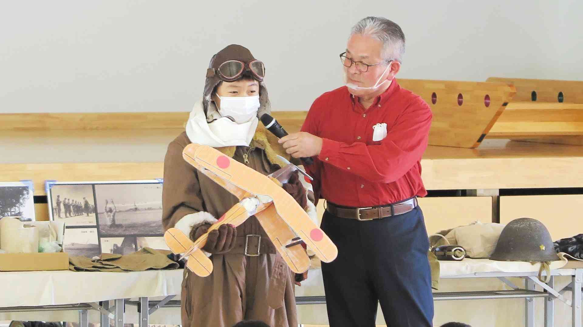 筆者（右）らが合志楓の森小で行った出前平和講座の模様。児童（左）が着ているのは陸軍航空防寒服＝2020年10月