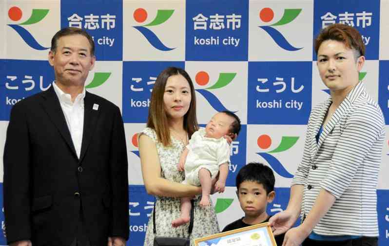 6万5千人目の合志市民となった男児（左から3人目）とその家族。左端は荒木義行市長＝20日、合志市