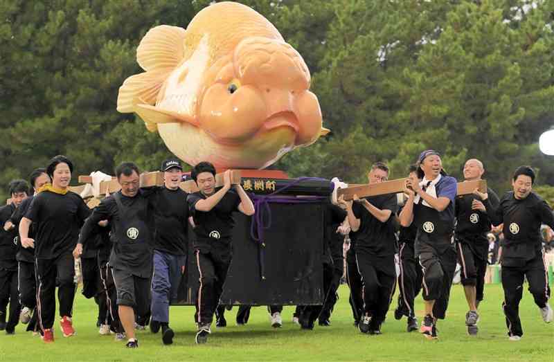 重さ約300キロの金魚みこしを担いで走る参加者＝8月24日、長洲町