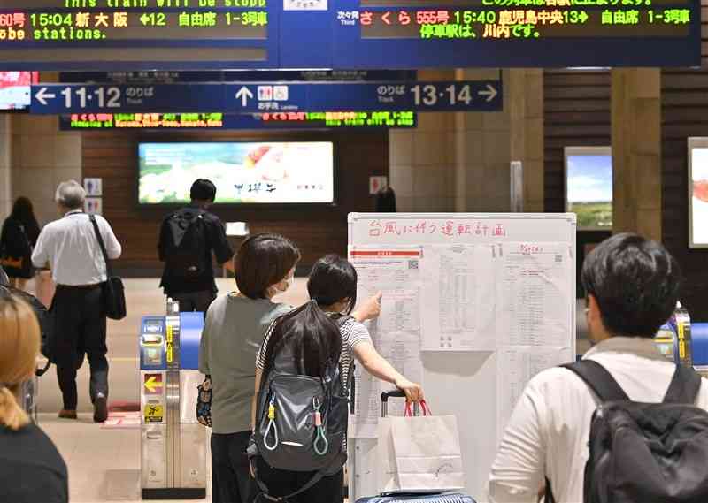 九州新幹線の改札前で、台風10号に伴う運行計画を確認する利用客たち＝28日午後、熊本市西区のJR熊本駅（上杉勇太）