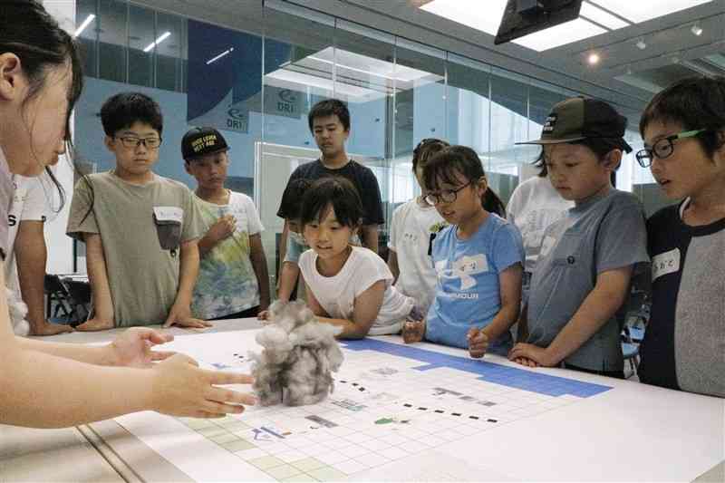 ゲリラ豪雨について学ぶワークショップで、雨雲の模型を見る小学生ら＝神戸市の「人と防災未来センター」