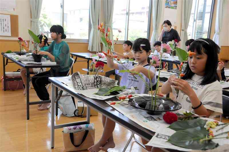 花の特徴を観察しながら思い思いに花を生ける小学生たち＝8月24日、熊本市東区