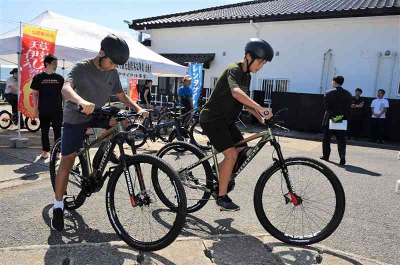 電動アシスト付きマウンテンバイクに試乗する地元中学生たち＝1日、苓北町