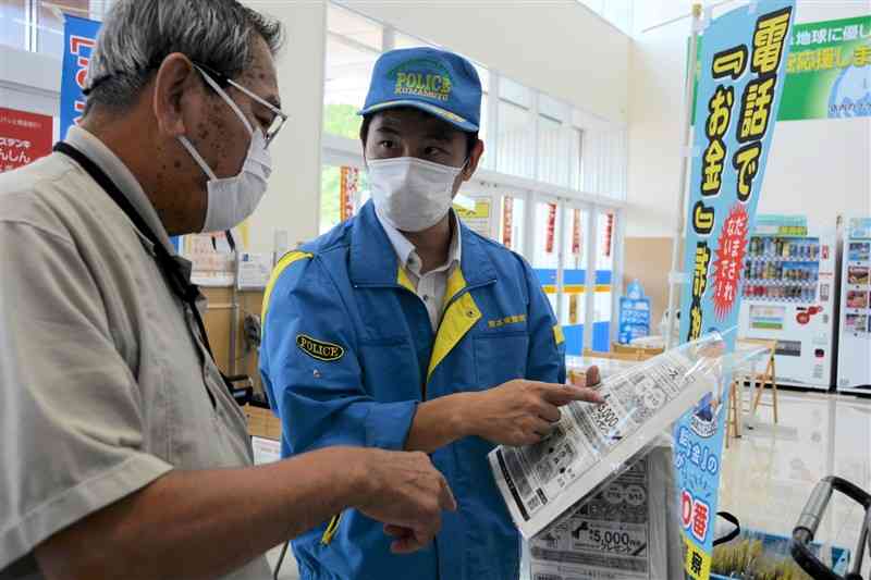 買い物客（左）に防犯機能付き電話機の効果について説明する人吉署員＝1日、人吉市