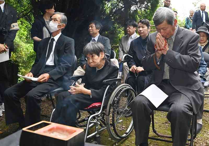 水俣病犠牲者慰霊祭で、乙女塚に手を合わせる胎児性患者の坂本しのぶさん（中央）ら。患者の高齢化が進んでいる＝5月、水俣市（石本智）