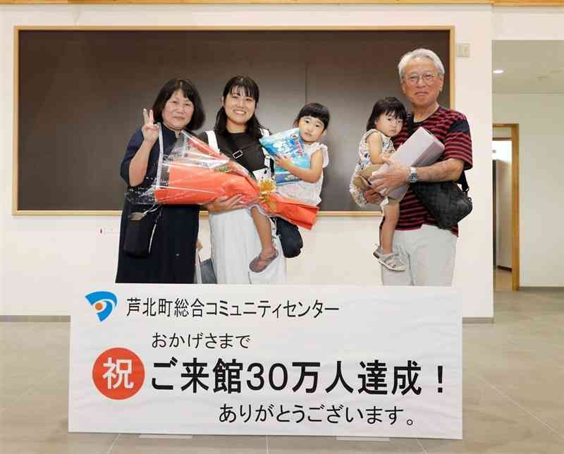 30万人目の来館者となり、花束を受け取った原田由起さん（左から2人目）ら＝8月30日、芦北町