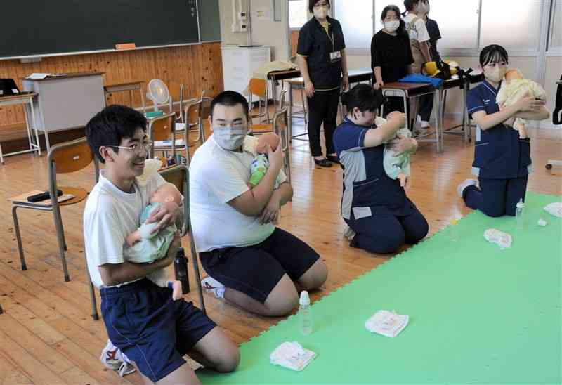 高校生の指導で赤ちゃんの世話や抱っこの仕方を学ぶ中学生ら＝4日、阿蘇市