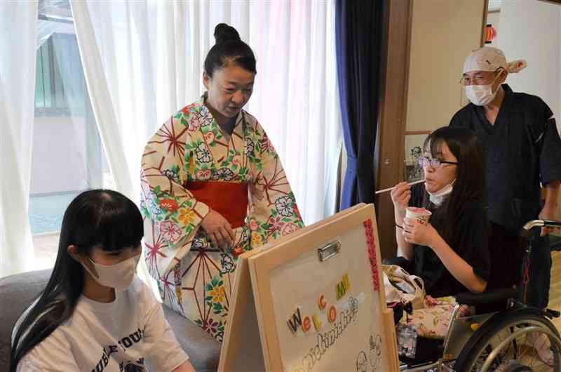 ニチニチが開いた縁日で、看板を作って準備をする毛利和子さん（左から2人目）や入院を経験した若者ら＝8月25日、熊本市中央区