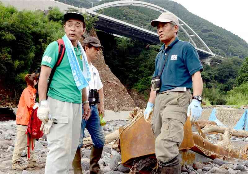 阿蘇大橋下流の白川沿いで、行方不明になった大和晃さんの手掛かりを探す父の卓也さん（左手前）＝2016年7月、大津町