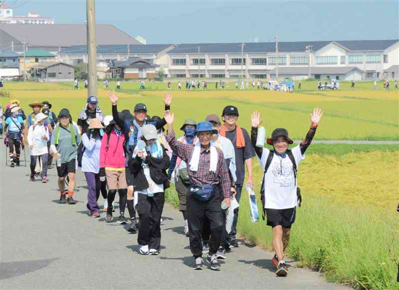 田んぼ沿いの道を笑顔で歩く10キロコースの参加者＝7日、阿蘇市