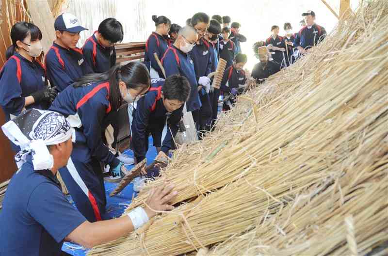 職人に学びながら、かやぶき体験をする南阿蘇中の生徒ら＝13日、阿蘇市