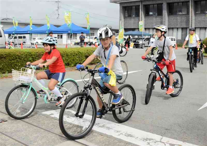 クイズを解きながら得点を競う自転車イベントでスタートする参加者＝14日、阿蘇市