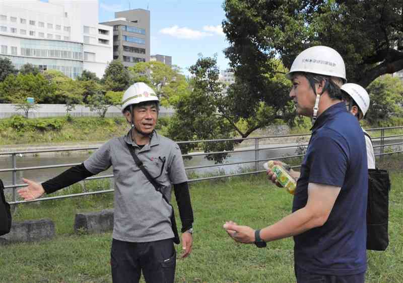 「緑の区間」の工事担当者（左）から説明を聞く保護者ら＝14日、熊本市中央区