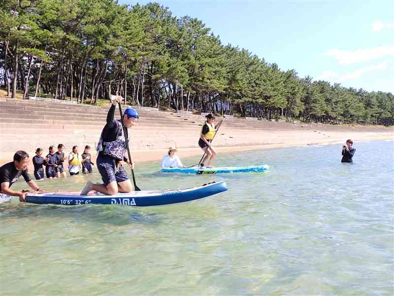 白鶴浜海水浴場でSUPを体験する天草中の生徒＝12日、天草市（同中提供）