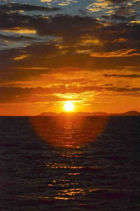 オレンジ色の光で海を照らしながら沈む夕日。10月からは水平線に夕日が沈む様子を見ることができるという＝14日、苓北町