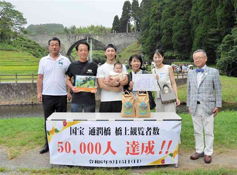 通潤橋の橋上部の観覧者で5万人目となった福岡和弥さん（左から3人目）＝15日、山都町